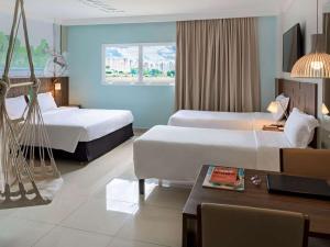 a hotel room with two beds and a table at Golden Tower Maurilio Biagi by Fênix Hotéis in Ribeirão Preto