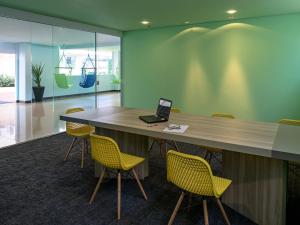 a desk with yellow chairs and a laptop on it at Golden Tower Maurilio Biagi by Fênix Hotéis in Ribeirão Preto