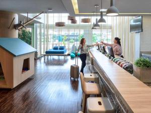 two women are waiting at a counter in an airport at Golden Tower Maurilio Biagi by Fênix Hotéis in Ribeirão Preto