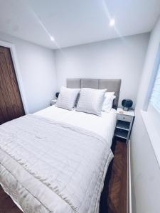 ein Schlafzimmer mit einem großen Bett mit weißer Bettwäsche in der Unterkunft Little Dunton Lodges 2 in Brentwood