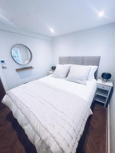 Schlafzimmer mit einem großen weißen Bett und einem Spiegel in der Unterkunft Little Dunton Lodges 2 in Brentwood