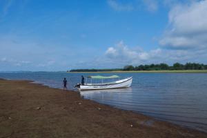 a man standing next to a boat on the shore at Serene Kabini Wild lodge in Kabini River