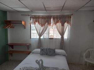 a bedroom with a bed and a window with curtains at Casa de Alexis in Puerto Baquerizo Moreno +11 photos