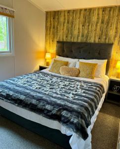 ein Schlafzimmer mit einem großen Bett mit einer Holzwand in der Unterkunft Ty Cwtch Cabin - secluded woodland cabin & covered hot tub in Moffat