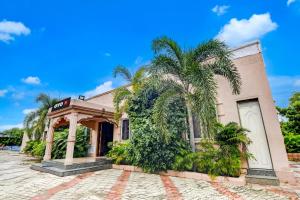 a building with a palm tree in front of it at Hotel O Nilkanth Nivas in Puri