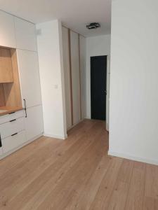 an empty room with white cabinets and a wooden floor at Old Town Apartment Elbląg in Elblag