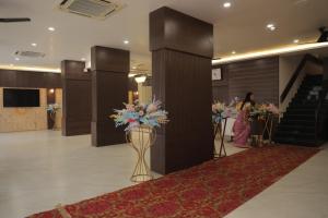 a lobby with a staircase and vases of flowers at The Moris palace hotel in Rajkot