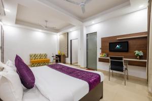 a bedroom with a bed and a desk and a tv at Hotel Aura Grand sector 63A Noida I Couple Friendly in Noida