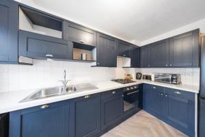 a kitchen with dark blue cabinets and a sink at Cozy Two Bedroom House with Driveway Parking & Garden in Chatham