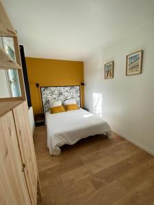 ein Schlafzimmer mit einem Bett mit gelben Wänden und Holzböden in der Unterkunft Les Frimousses in Cabourg