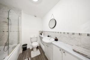 a bathroom with a toilet and a sink and a mirror at Cozy Two Bedroom House with Driveway Parking & Garden in Chatham