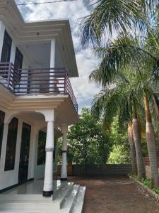a house with a balcony and a palm tree at Hidalgo Home Apartment's in Moshi