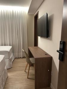 Una habitación de hotel con un escritorio y un televisor en la pared. en Belém Forest Inn, en Belém