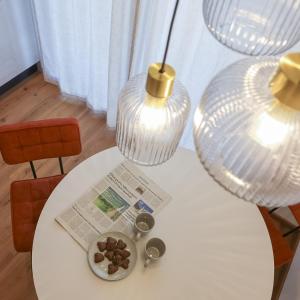 ブレッサノーネにあるecHo Apartments & SPAの2つのランプと新聞が置かれた白いテーブル