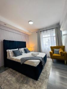 a bedroom with a large bed and a yellow chair at Getaways homes in Nairobi