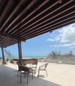 a patio with chairs and a table with a view of the ocean at Pousada Vista Encantada Preá in Cruz