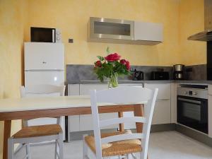 a kitchen with a table and chairs with a vase of flowers at Logement indépendant dans cité médiévale in La Charité-sur-Loire