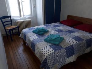 a bedroom with a bed with two green towels on it at Logement indépendant dans cité médiévale in La Charité-sur-Loire