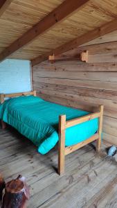 ein Bett in einem Holzzimmer in einer Hütte in der Unterkunft Ecos Casas de Montaña in Sierra de la Ventana