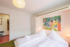 a bedroom with a white bed with a painting on the wall at Brentsch B51 in Scuol +16 photos