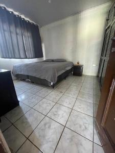 ein Schlafzimmer mit einem Bett und einem gefliesten Boden in der Unterkunft Casa ampla e aconchegante in Foz do Iguaçu