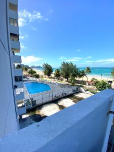 a balcony with a view of a swimming pool and the beach at Oceanfront Isla Verde 2B 2B Apartment Paradise Getaway in San Juan