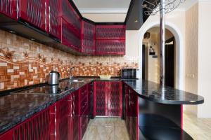 a kitchen with red cabinets and black counter tops at 1 bedroom Modern, Sunny apartment in Amiryan street AM104 in Yerevan
