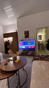 ein Wohnzimmer mit Tisch und Fernseher in der Unterkunft شقة حي البوادي in Dschidda