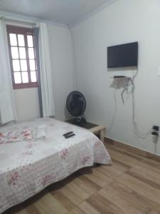a bedroom with a bed and a flat screen tv at Kitnet manacá in Paraty
