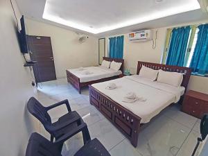 een slaapkamer met twee bedden en een stoel erin bij Flora inn in Ankola