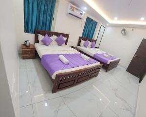 2 bedden in een kamer met paarse lakens en kussens bij Flora inn in Ankola