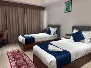 a hotel room with two beds with blue and white sheets at Hotel Amyra in Kota +8 photos