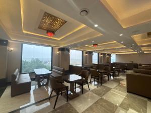 a restaurant with tables and chairs and large windows at Hotel Amyra in Kota