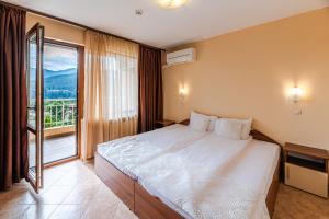 a bedroom with a large bed and a large window at ArdoVel Park Hotel in Velingrad +8 photos