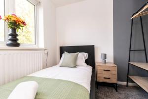 a bedroom with a bed and a vase of flowers on a window at Cherry House in Durham