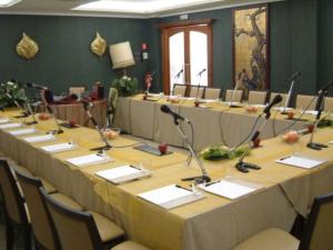 une grande salle de conférence avec une grande table et des microphones dans l'établissement Regent Beachotel, à Reggio de Calabre