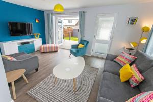 una sala de estar con un sofá y una mesa en Sandbanks Braunton, Stylish Cottage near to Saunton Beach Sleeps 4, en Croyde