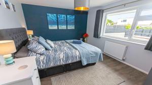 Un dormitorio con una cama y un sofá y una ventana. en Sandbanks Braunton, Stylish Cottage near to Saunton Beach Sleeps 4, en Croyde