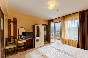 a bedroom with a bed and a desk and a television at ArdoVel Park Hotel in Velingrad