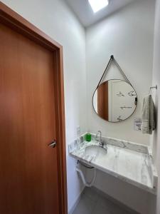 ein Badezimmer mit Waschbecken und Spiegel an der Wand in der Unterkunft Morada da Fé I 300 m da Canção Nova Cond Da fé in Cachoeira Paulista