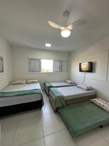 ein Schlafzimmer mit drei Betten und einem Deckenventilator in der Unterkunft Morada da Fé I 300 m da Canção Nova Cond Da fé in Cachoeira Paulista