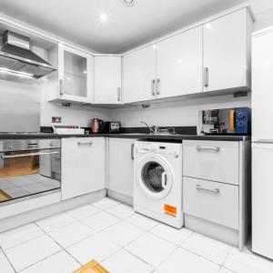 eine Küche mit weißen Schränken und einer Waschmaschine in der Unterkunft Stylish Two Bed Apartment - Speed Wi-Fi - Smart Tv - Parking 201MH in Birmingham