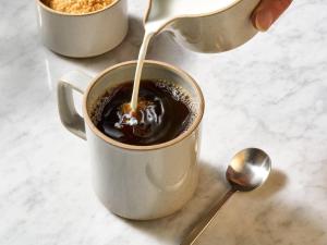 アレクサンドリアにあるFairfield Inn & Suites by Marriott Alexandria West/Mark Centerのコーヒーにミルクを注いでいる