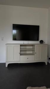 un centro de entretenimiento blanco con TV de pantalla plana. en Ferienwohnung Fischer, en Stolberg