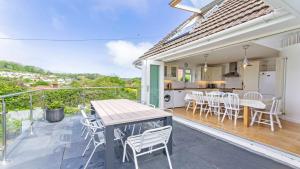 een patio met een tafel en stoelen en een keuken bij Rooftops Braunton, Stylish Beach House - Fantastic Views - Hot Tub hire - Sleeps 8 in Braunton