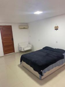 a bedroom with a bed and a door and a chair at Apartamento espaçoso e bem localizado in Boa Vista