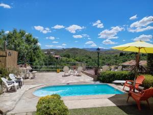 a swimming pool with chairs and an umbrella at Cerros Azules in Trapiche