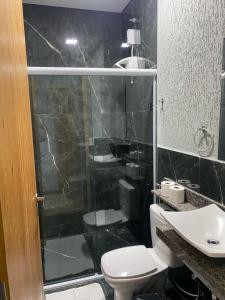 a bathroom with a shower and a toilet and a sink at Hotel Sol Nascente in Assaí