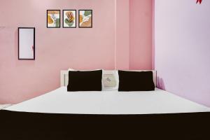 a bedroom with a white bed with a clock on it at SPOT ON Pradhan Hotel in Bhīta