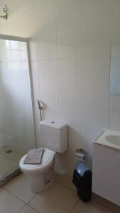 a white bathroom with a toilet and a sink at Barão do Vale in Itaipava